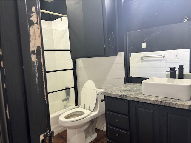 full bathroom featuring tile walls, toilet, vanity, and tiled shower / bath combo