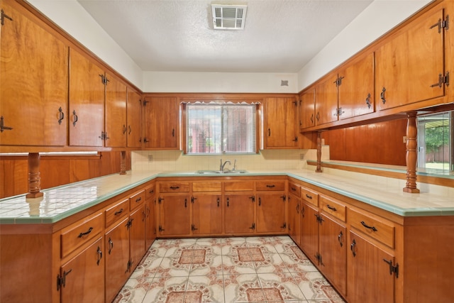 kitchen featuring backsplash, a textured ceiling, and sink