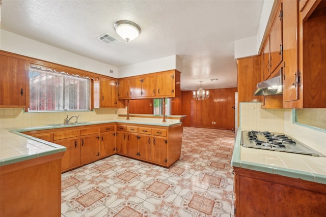 kitchen with white gas cooktop, kitchen peninsula, tile counters, and backsplash