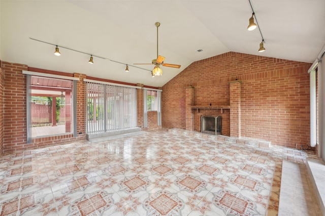 unfurnished living room with rail lighting, a brick fireplace, and plenty of natural light