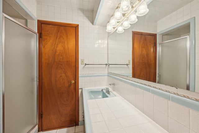 bathroom with a shower with door, tile walls, tile patterned flooring, and vanity