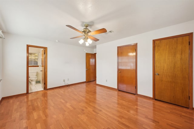 unfurnished bedroom featuring ensuite bathroom, light wood-type flooring, and ceiling fan