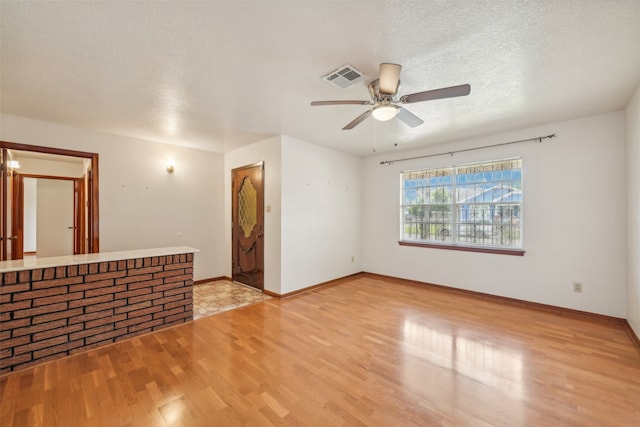 unfurnished room featuring light hardwood / wood-style floors, a textured ceiling, bar area, and ceiling fan