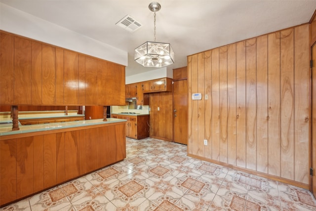 kitchen featuring kitchen peninsula, decorative light fixtures, a chandelier, and wooden walls