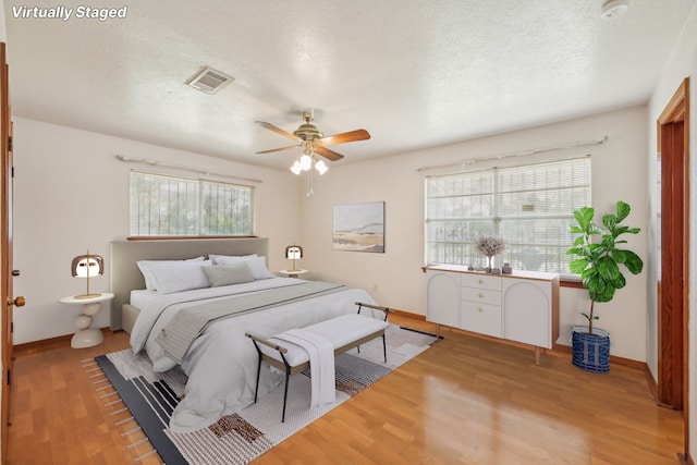 bedroom with light hardwood / wood-style floors, a textured ceiling, and ceiling fan