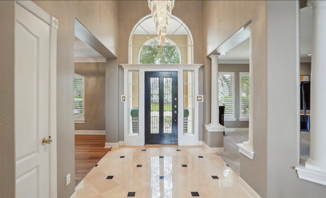 entrance foyer featuring crown molding, ornate columns, hardwood / wood-style flooring, and a chandelier