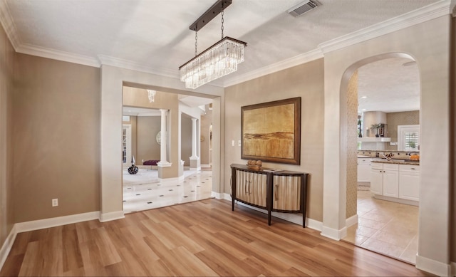 interior space with crown molding, a notable chandelier, and light hardwood / wood-style flooring