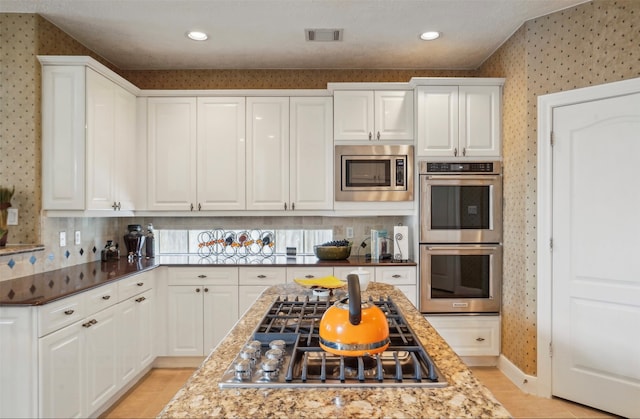 kitchen featuring light stone countertops, appliances with stainless steel finishes, and white cabinets