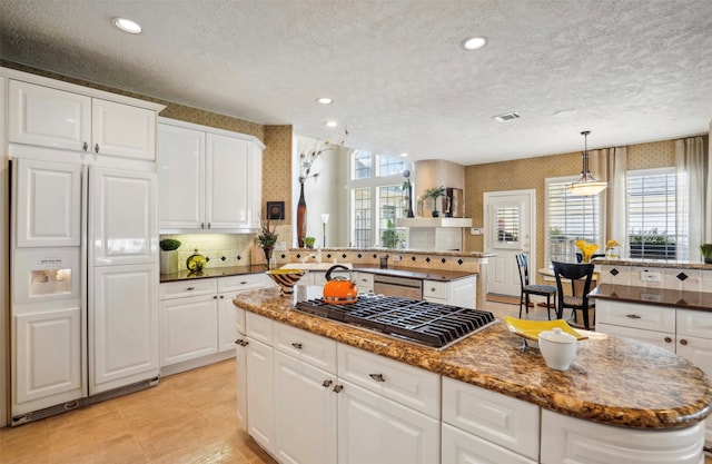 kitchen with stainless steel appliances, a healthy amount of sunlight, decorative light fixtures, and a kitchen island