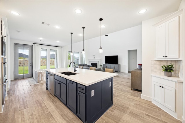 kitchen with sink, white cabinetry, a center island with sink, and tasteful backsplash