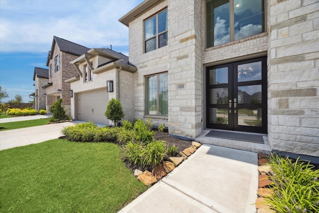 view of exterior entry with french doors, a yard, and a garage