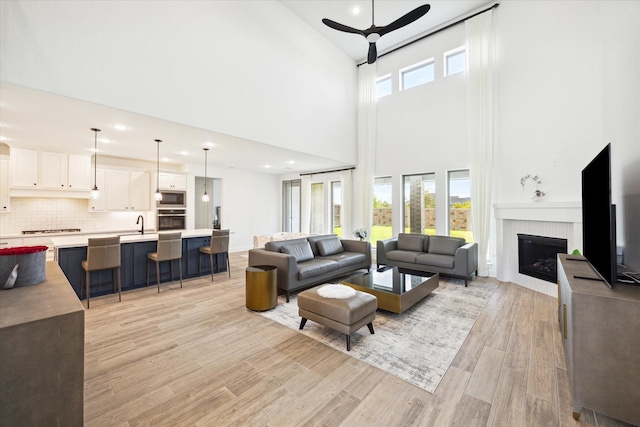 living room featuring ceiling fan, sink, and light hardwood / wood-style flooring