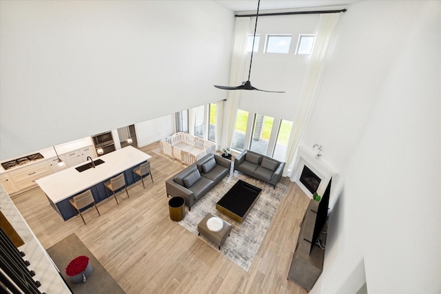 living room with a towering ceiling, hardwood / wood-style flooring, sink, and a healthy amount of sunlight