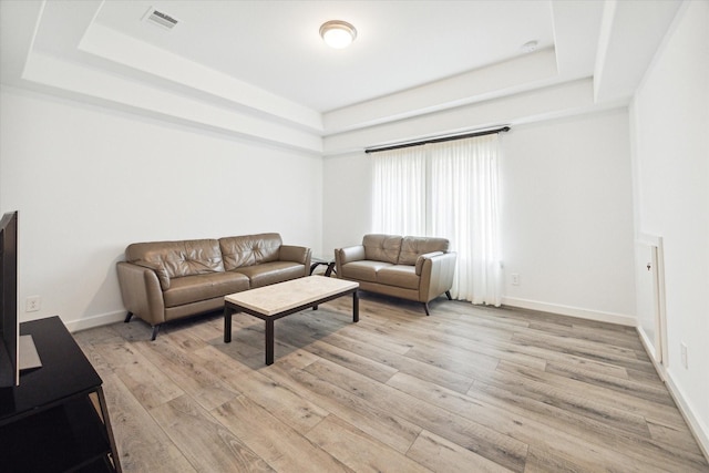 living room featuring a tray ceiling and light hardwood / wood-style floors