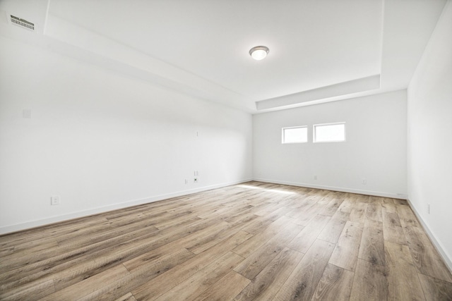 unfurnished room featuring light wood-type flooring and a tray ceiling