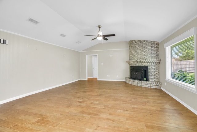 unfurnished living room featuring vaulted ceiling, a brick fireplace, light hardwood / wood-style flooring, and ceiling fan