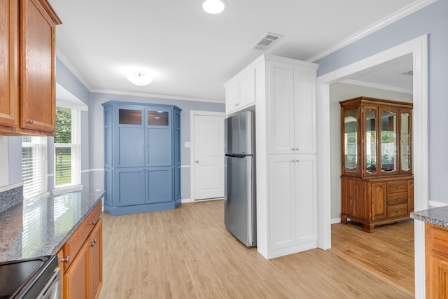 kitchen featuring light hardwood / wood-style flooring, ornamental molding, appliances with stainless steel finishes, and dark stone counters