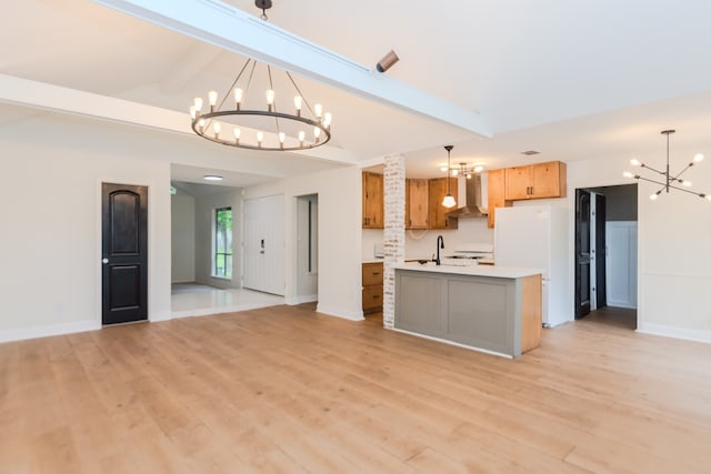 kitchen with hanging light fixtures, beam ceiling, light wood-type flooring, and wall chimney exhaust hood