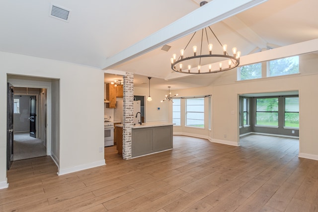 unfurnished living room with an inviting chandelier, sink, beamed ceiling, and light hardwood / wood-style flooring