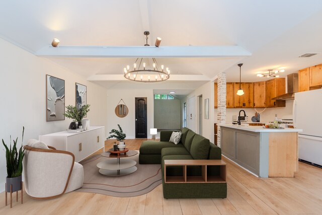 living room with a notable chandelier, sink, beam ceiling, and light wood-type flooring