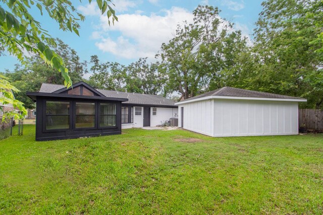 rear view of house featuring central air condition unit and a lawn