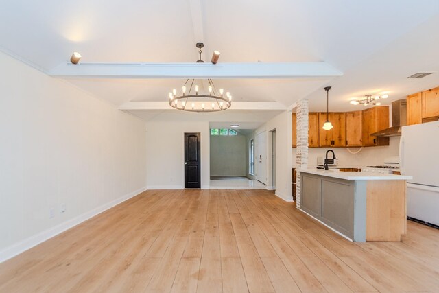 kitchen with beamed ceiling, light hardwood / wood-style flooring, wall chimney range hood, hanging light fixtures, and white fridge