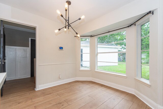 unfurnished dining area featuring light hardwood / wood-style flooring, an inviting chandelier, and plenty of natural light