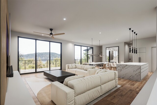 living room with a mountain view, ceiling fan with notable chandelier, a wealth of natural light, and light hardwood / wood-style flooring