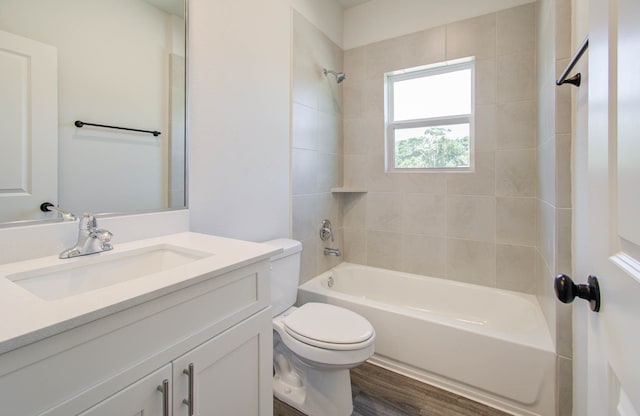 full bathroom with tiled shower / bath, vanity, hardwood / wood-style floors, and toilet