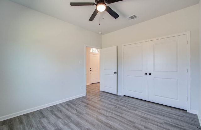 unfurnished bedroom with a closet, light wood-type flooring, and ceiling fan