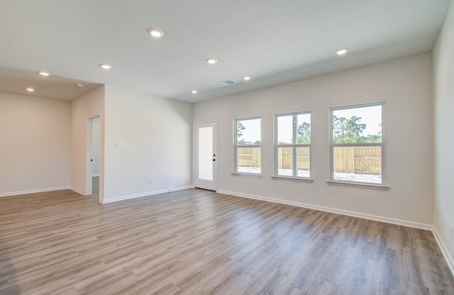 spare room featuring light wood-type flooring and a healthy amount of sunlight