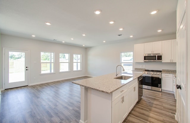 kitchen with stainless steel appliances, a center island with sink, sink, and a healthy amount of sunlight