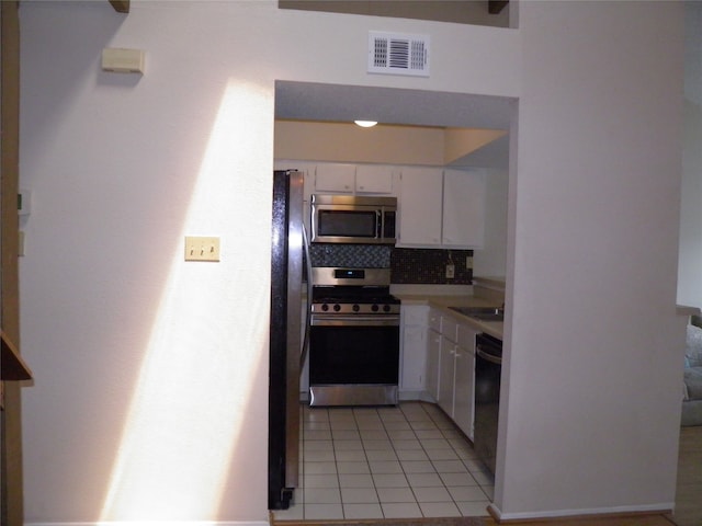 kitchen featuring decorative backsplash, sink, black appliances, white cabinets, and light tile patterned floors