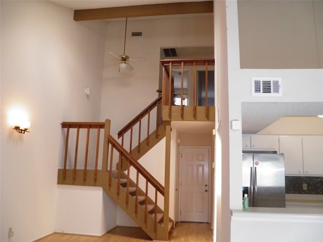 stairs with ceiling fan, vaulted ceiling, and hardwood / wood-style floors