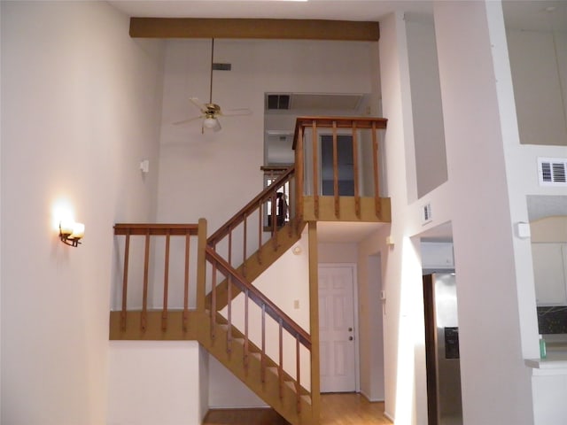 stairway featuring hardwood / wood-style floors, beam ceiling, high vaulted ceiling, and ceiling fan