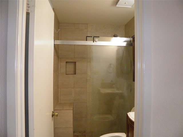 bathroom featuring an enclosed shower, toilet, and vanity