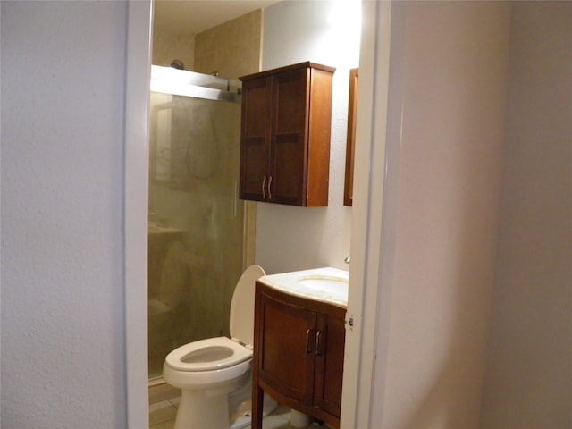 bathroom with tile patterned floors, a shower with shower door, vanity, and toilet