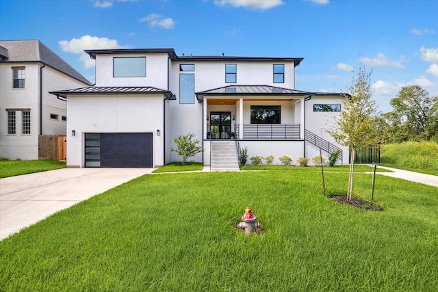 modern farmhouse featuring a garage, a front yard, and covered porch