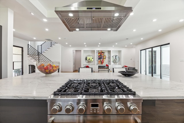 kitchen featuring light stone counters, a spacious island, and island range hood