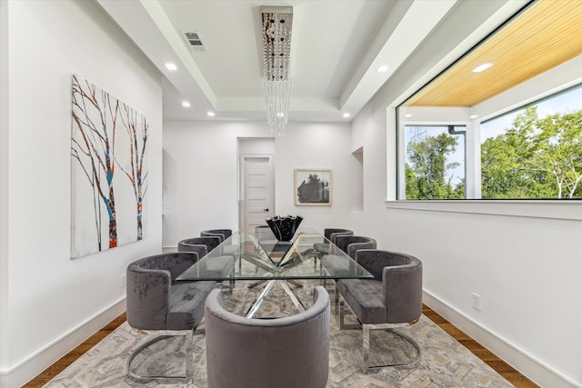 home office with an inviting chandelier, hardwood / wood-style flooring, and a tray ceiling