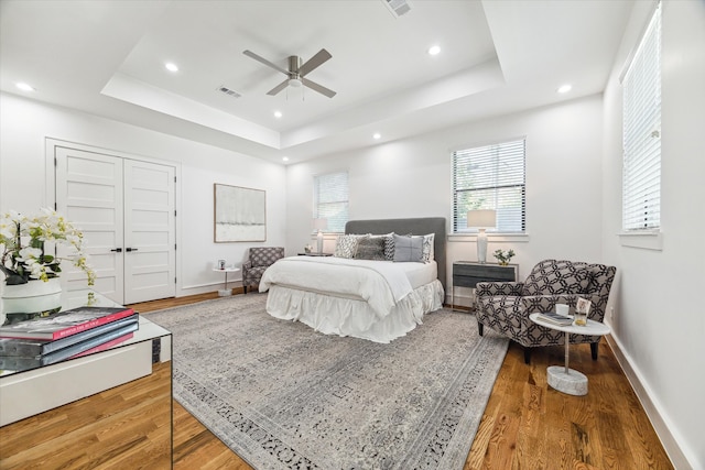 bedroom featuring wood-type flooring, ceiling fan, and a tray ceiling