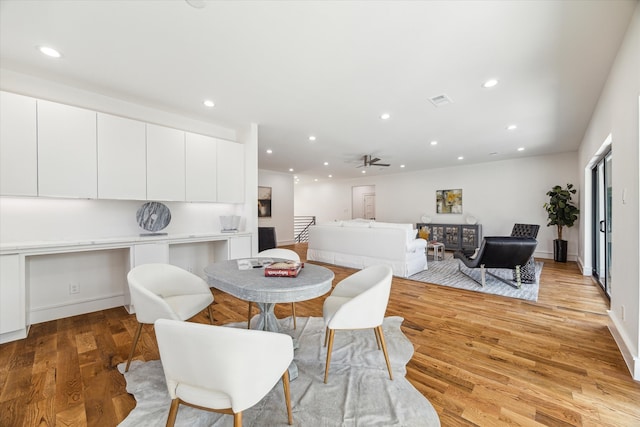 dining room with light wood-type flooring, ceiling fan, and built in desk