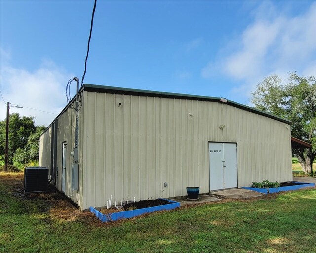 view of outbuilding featuring central air condition unit and a yard