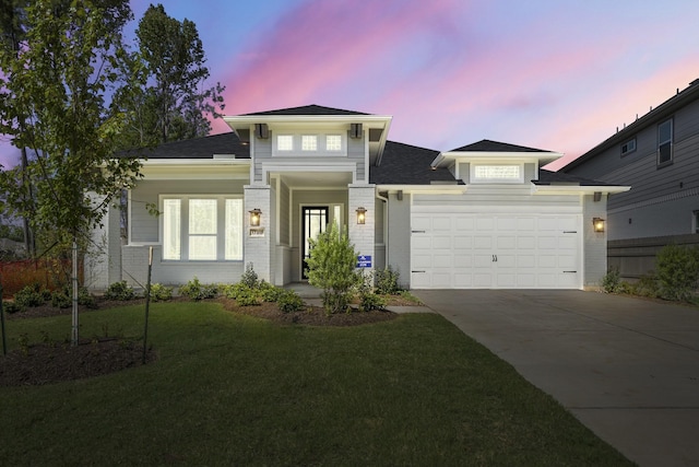 prairie-style home with a yard, concrete driveway, brick siding, and a garage