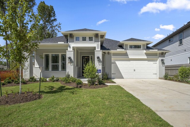 prairie-style home with a garage and a front lawn