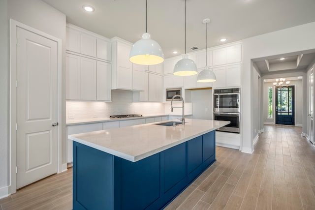 kitchen featuring tasteful backsplash, white cabinets, sink, light hardwood / wood-style floors, and appliances with stainless steel finishes