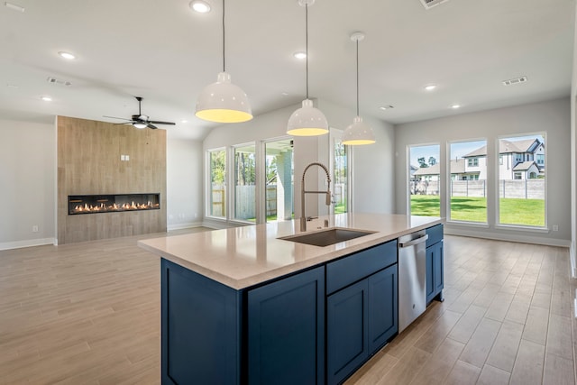 kitchen featuring a healthy amount of sunlight, sink, a fireplace, and a kitchen island with sink