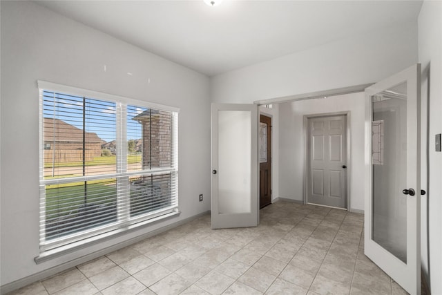 unfurnished bedroom with french doors, light tile patterned flooring, and baseboards