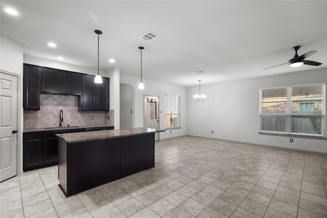 kitchen featuring a sink, visible vents, a center island, dark stone counters, and pendant lighting