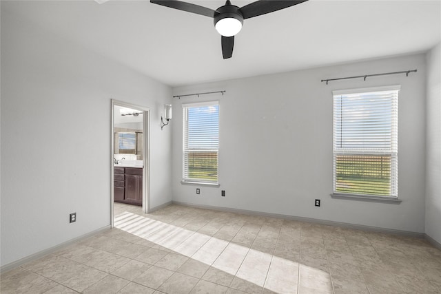 unfurnished bedroom with ensuite bathroom, a sink, a ceiling fan, and baseboards